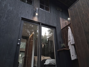 A modern interior with a glass door leading to a bedroom, wooden walls, and a towel rack.