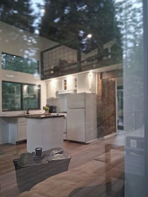 A modern kitchen with a central island, large windows, and a view of the outdoors.