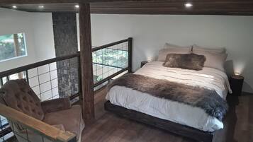 A bedroom with a bed, a chair, a nightstand, and a view through a window.