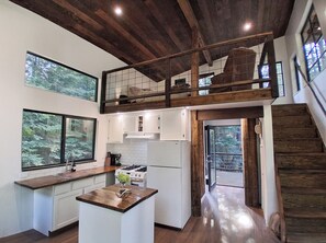 A modern kitchen with a central island, wooden beams, and large windows.