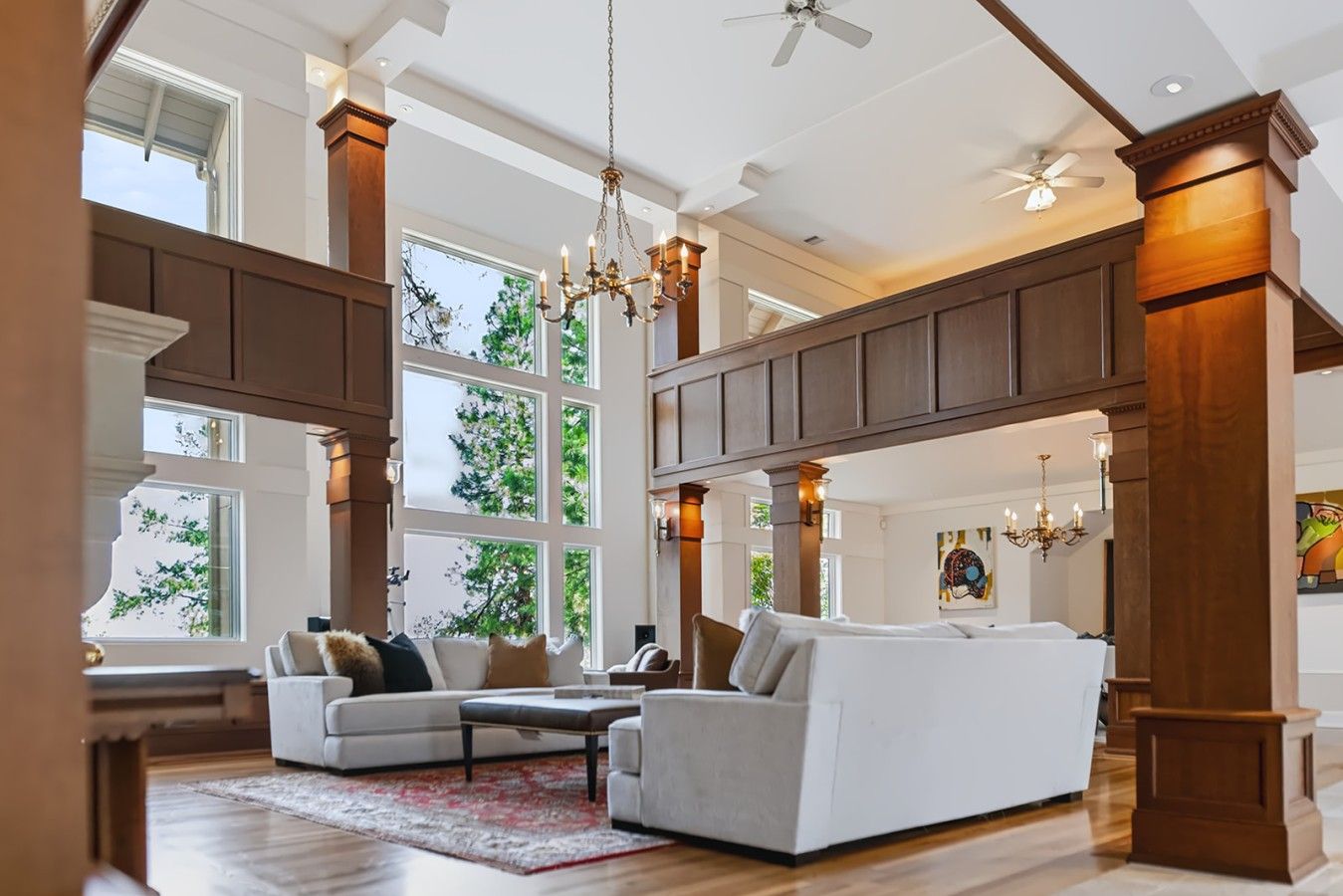 A spacious living room with high ceilings, large windows, and a chandelier.