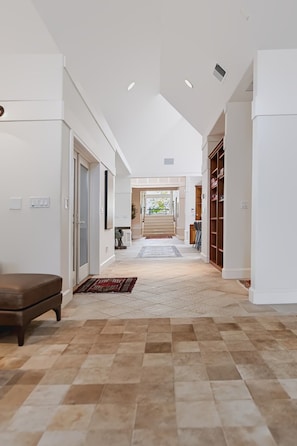 A spacious hallway with a checkered floor, a bench, and a staircase leading to a second floor. - Kai|Ridge At The Running Y (Klamath Falls)