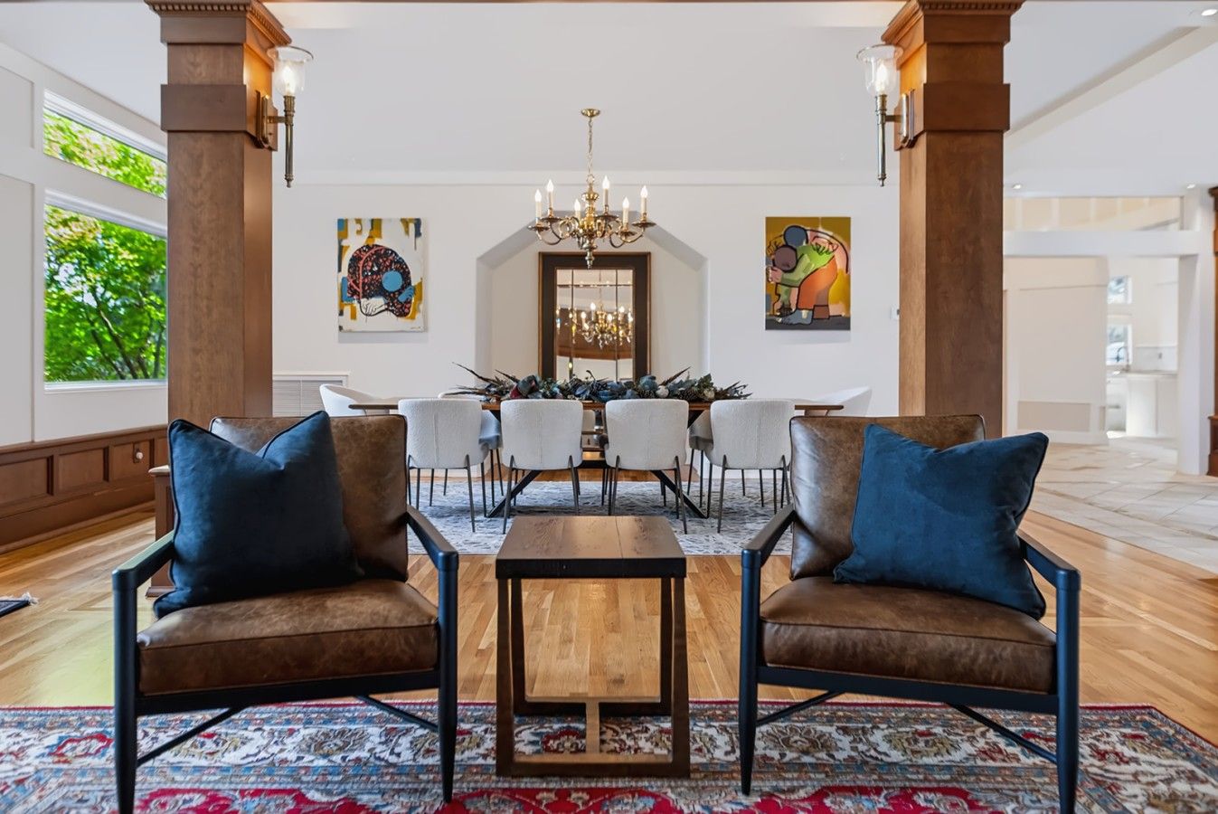 A spacious lobby with a dining area, two sofas, a chandelier, and artwork on the walls.