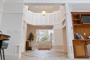A spacious interior with a staircase leading to an upper level, a chandelier, and a wooden cabinet with magazines. - Kai|Ridge At The Running Y (Klamath Falls)
