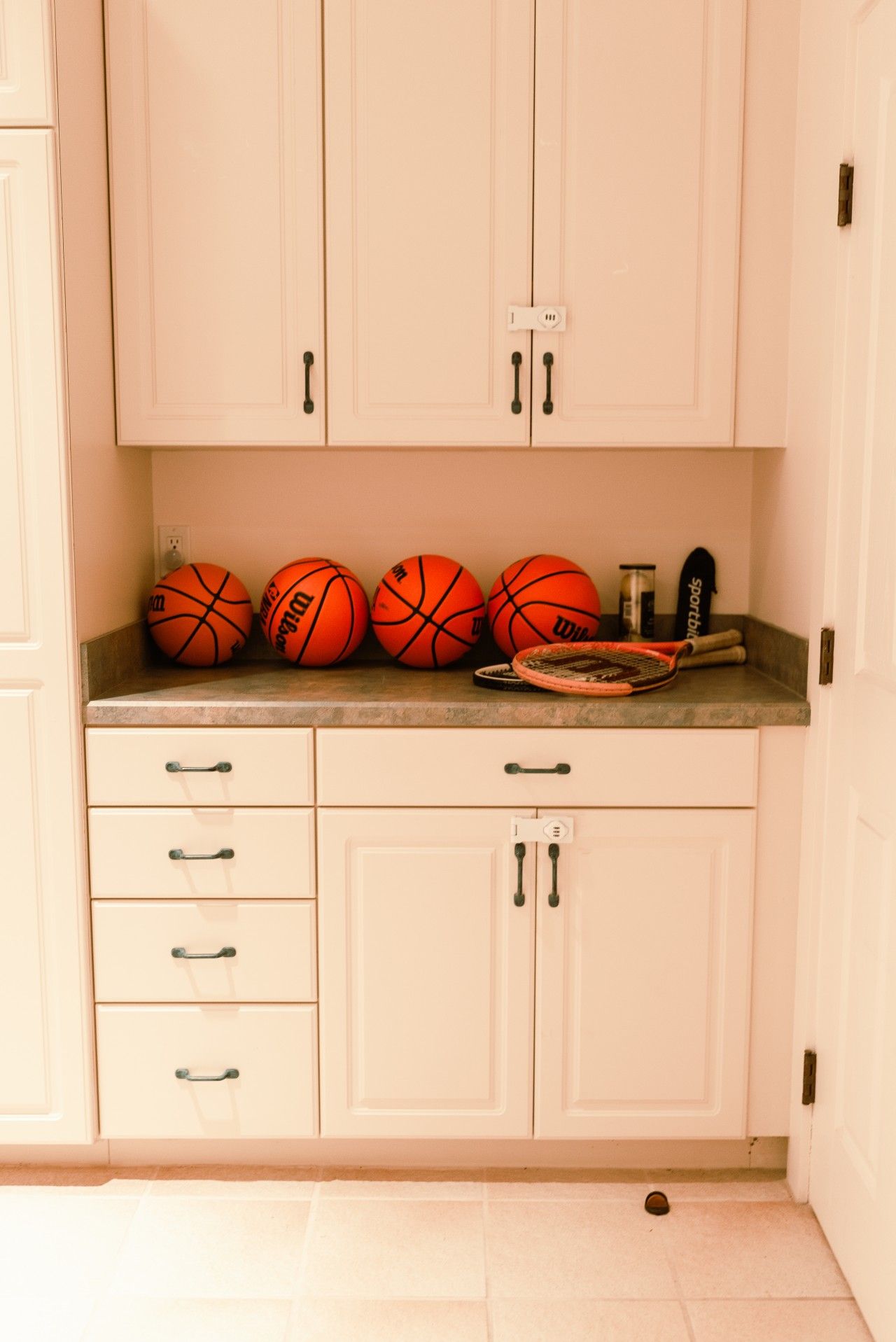 Een keuken met witte kastjes, een aanrecht en een basketbalring.