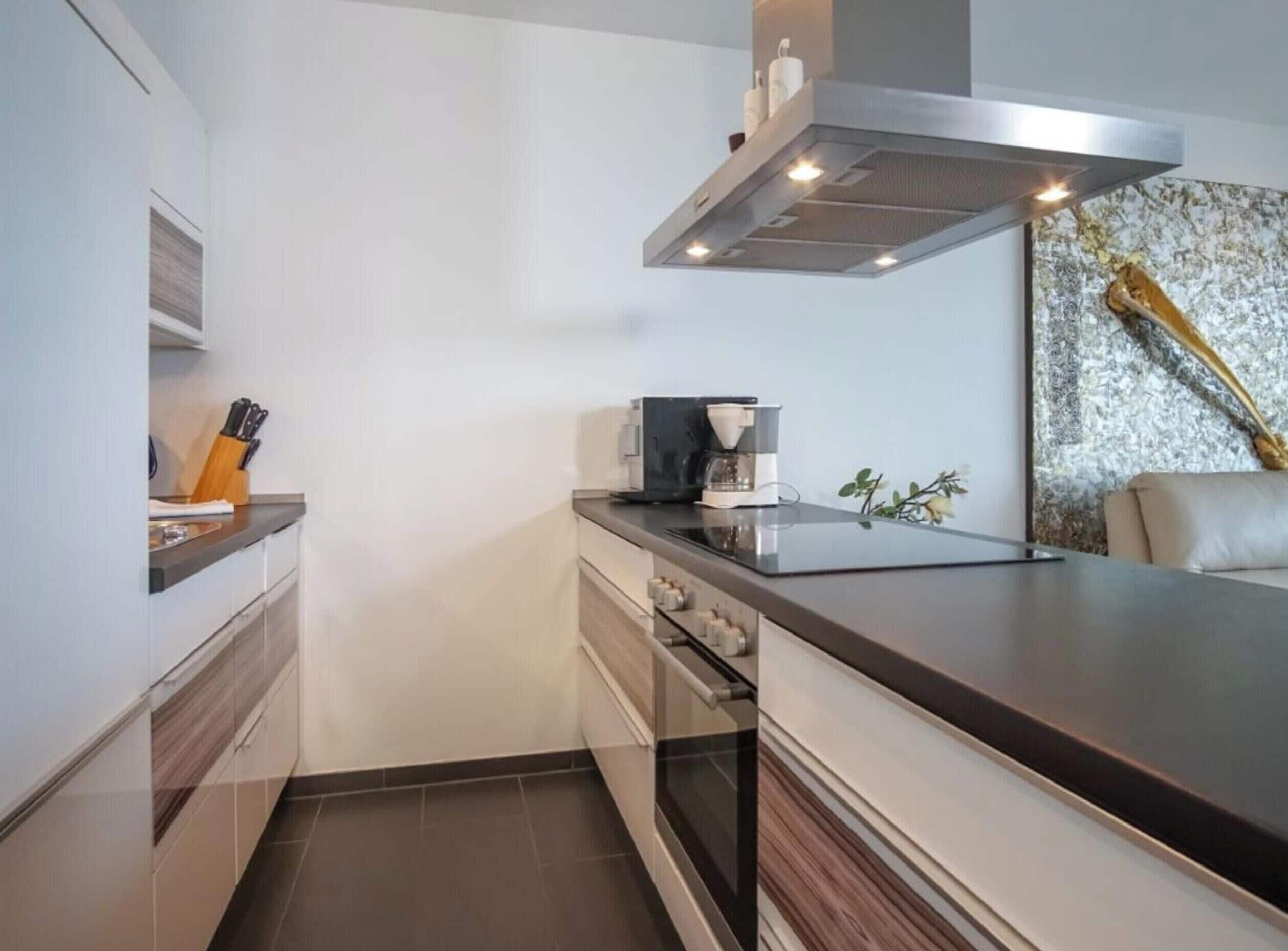 A modern kitchen with a built-in oven, a coffee maker, and a decorative wall piece.