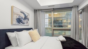 Ein Hotelzimmer mit Bett, einem Bild an der Wand und Blick durch ein großes Fenster.