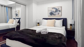 Ein Hotelzimmer mit einem Bett, Nachttischlampen, einem Spiegel und einem Bild an der Wand.