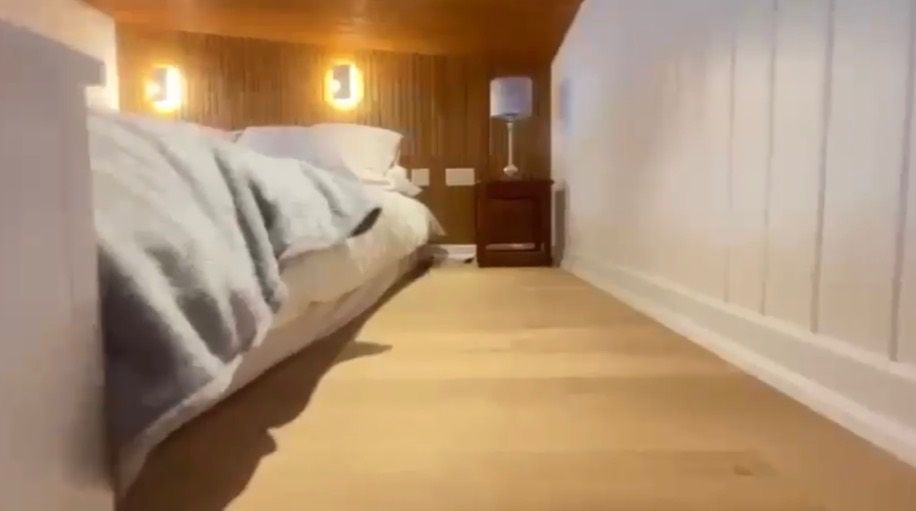 Una camera d'albergo con un letto, un comodino e una lampada.