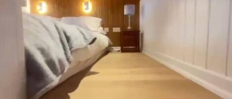 A hotel room with a bed, a nightstand, and a lamp.