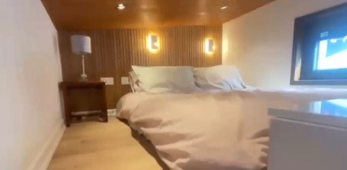 Una camera da letto con un letto, comodini e una TV a parete.