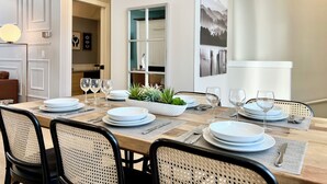 A dining area with a wooden table set for four, surrounded by wicker chairs. - Separate-Address Combo • Hot Tub • Parking • Air Conditioner, Sleeps up to 17 (Harvie Heights)