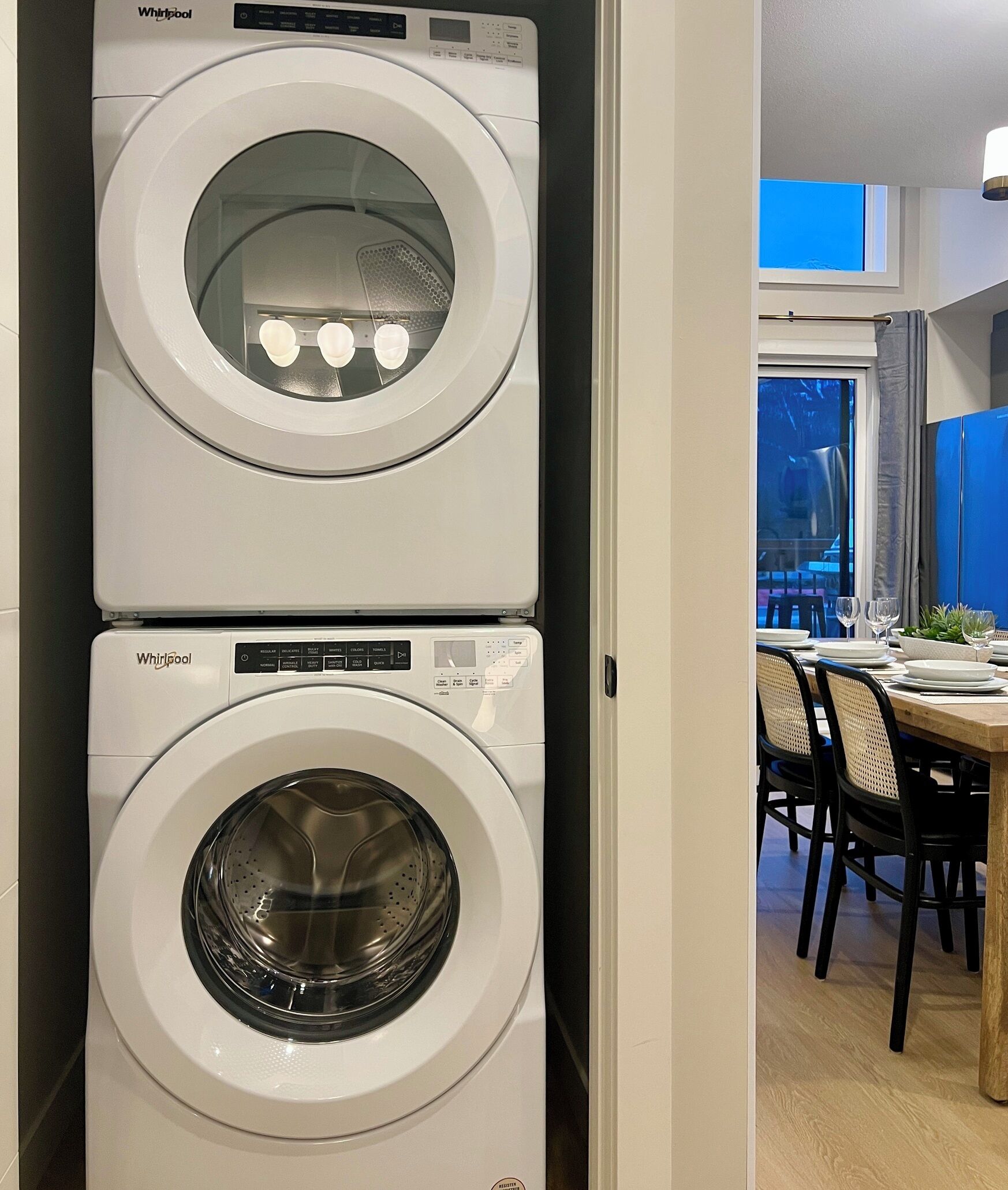 Un appareil combiné lave-linge et sèche-linge, de type superposé, installé dans un logement résidentiel.