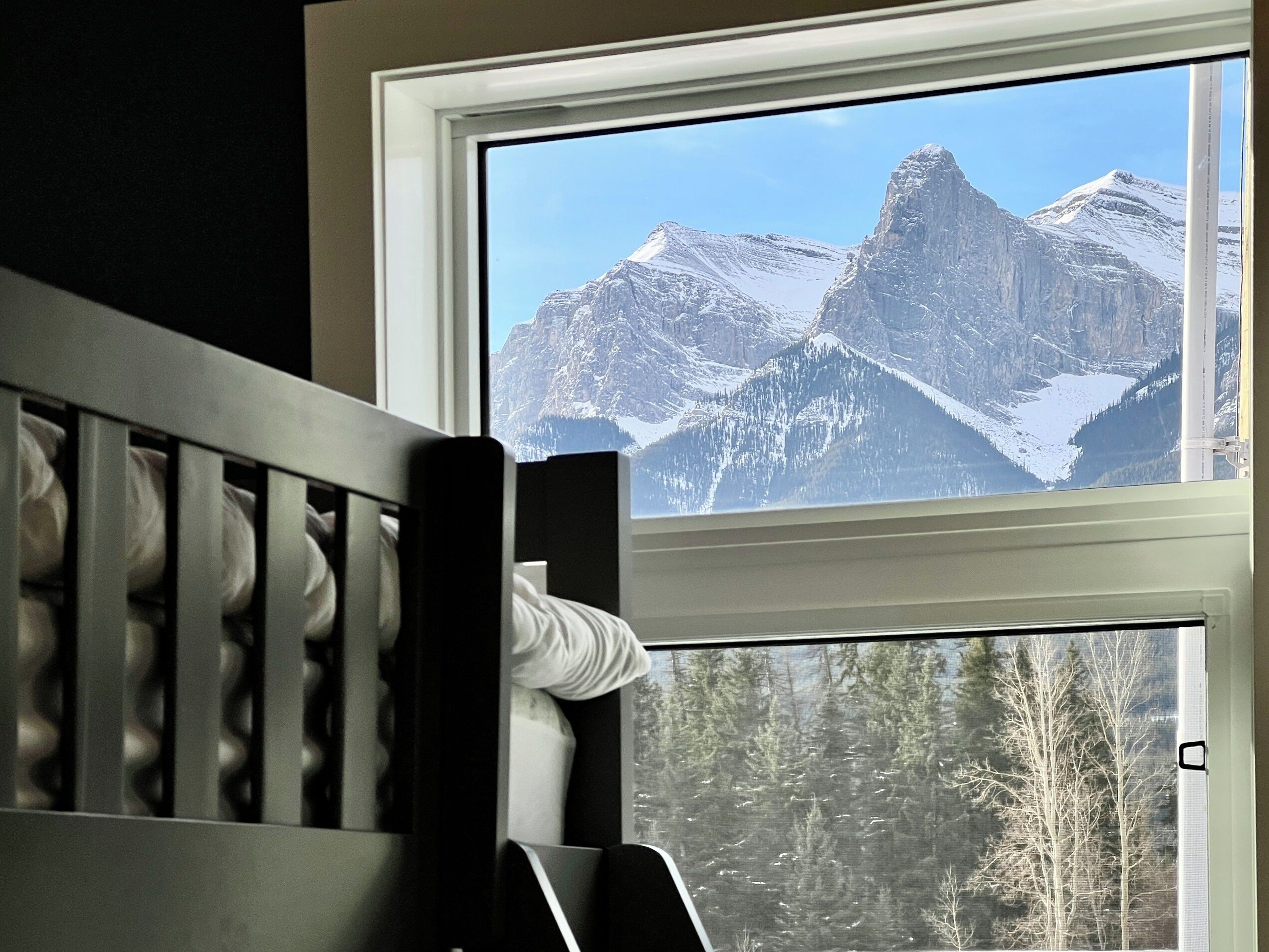 Une chambre avec un berceau et une fenêtre donnant sur des montagnes enneigées.