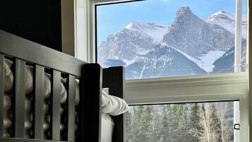 Une chambre avec un berceau et une fenêtre donnant sur des montagnes enneigées.