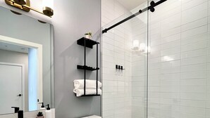 A modern bathroom with a glass shower enclosure, a toilet, a sink with a mirror, and a towel rack. - Separate-Address Combo • Hot Tub • Parking • Air Conditioner, Sleeps up to 17 (Harvie Heights)