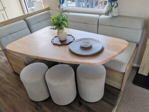 Un comedor con mesa de madera, asientos acolchados y una planta en maceta.