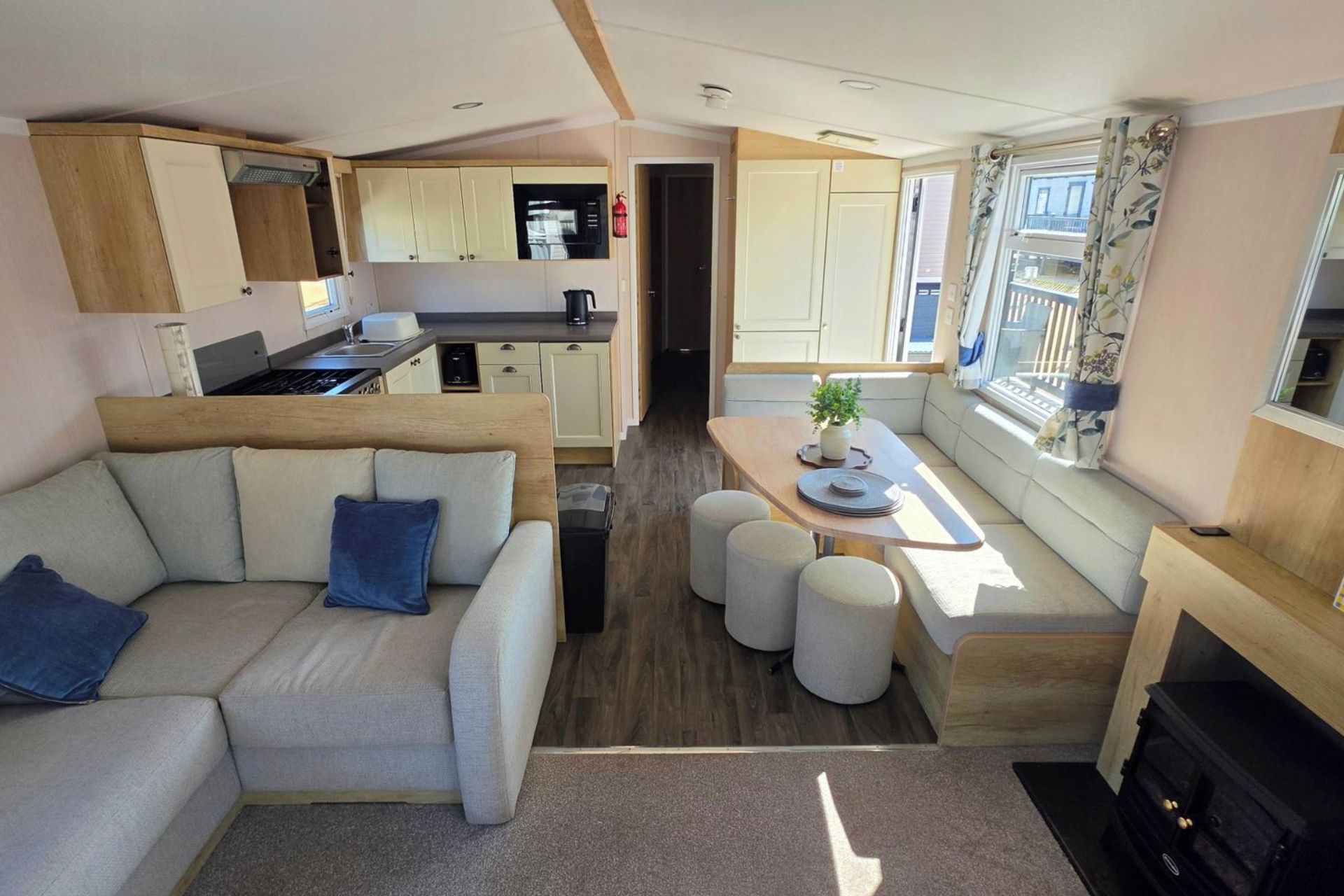 A compact living space with a sofa, ottomans, a dining table, a kitchen area, and a fireplace.