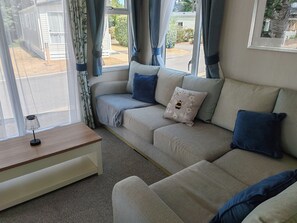 Uma sala de estar aconchegante com sofá seccional, uma mesinha e uma janela com cortinas.