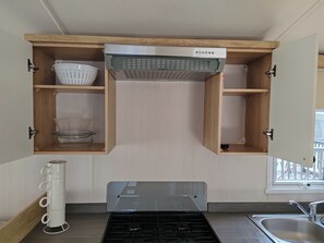 Una cocina con armarios de madera, extractor de humos empotrado y pileta de acero inoxidable.