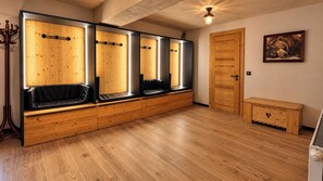 Una habitació amb zona d'seure amb una banca de fusta, una porta de fusta i un quadre a la paret.