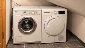 A front-loading washing machine and dryer side by side in a laundry room with tiled flooring. - 6 Bedroom Chalet - Stunning Sauna- Morzine-Avoriaz (Morzine)