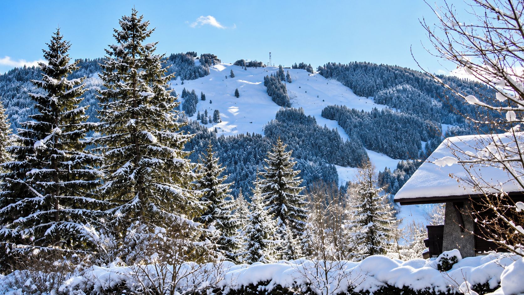 A snow-covered mountain landscape with a cabin in the foreground.
