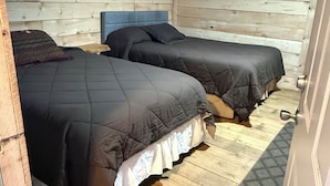 Quarto com duas camas, paredes e piso de madeira.