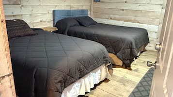 Ein Zimmer mit zwei Betten, Holzwänden und Holzdielen.