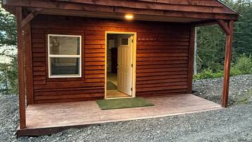 Eine kleine Holzhütte mit einer Tür, einem Fenster und einer Veranda.