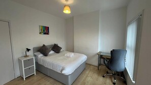 A bedroom with a bed, bedside table, chair, and a painting on the wall. - Apartment Sleeps 4 near Anfield (Liverpool)