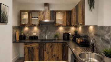 A modern kitchen with wooden cabinets, a stainless steel sink, and under-cabinet lighting.