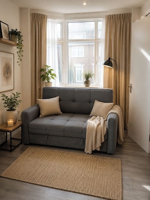 A modern living room with a grey sofa, beige cushions, a woven rug, and a floor lamp. - House Sleeps 7 with WiFi (Feltham)