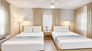 Une chambre d’hôtel avec deux lits, un ventilateur de plafond, des lampes de chevet et une fenêtre avec des rideaux.