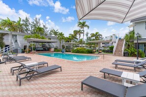A pool area with lounge chairs, a swimming pool, and a covered seating area.