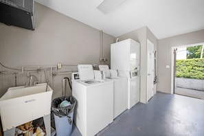 A laundry room with a washing machine, dryer, and a utility sink. - Stylish Two‑Queen Bed Studio steps from the Ocean (Pompano Beach)