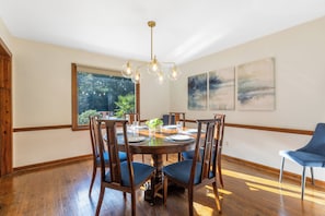 A dining room with a round table, wooden chairs, and a chandelier. - Whispering Pines- 5Br Wooded Retreat in Cary (Cary)