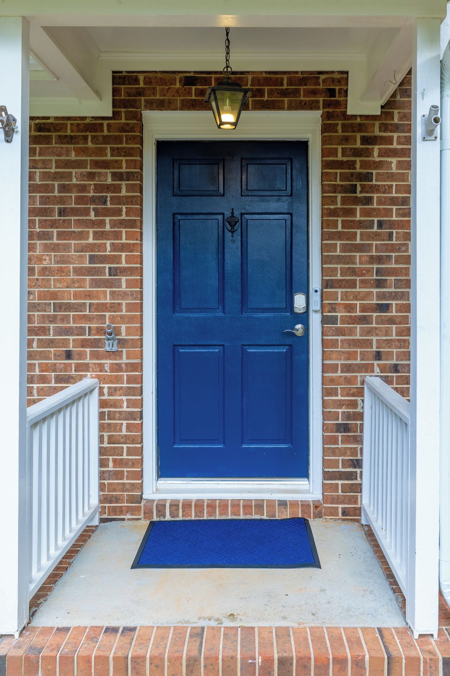 A blue door with a white-framed entrance, a metal door knocker, and a blue mat at the entrance.