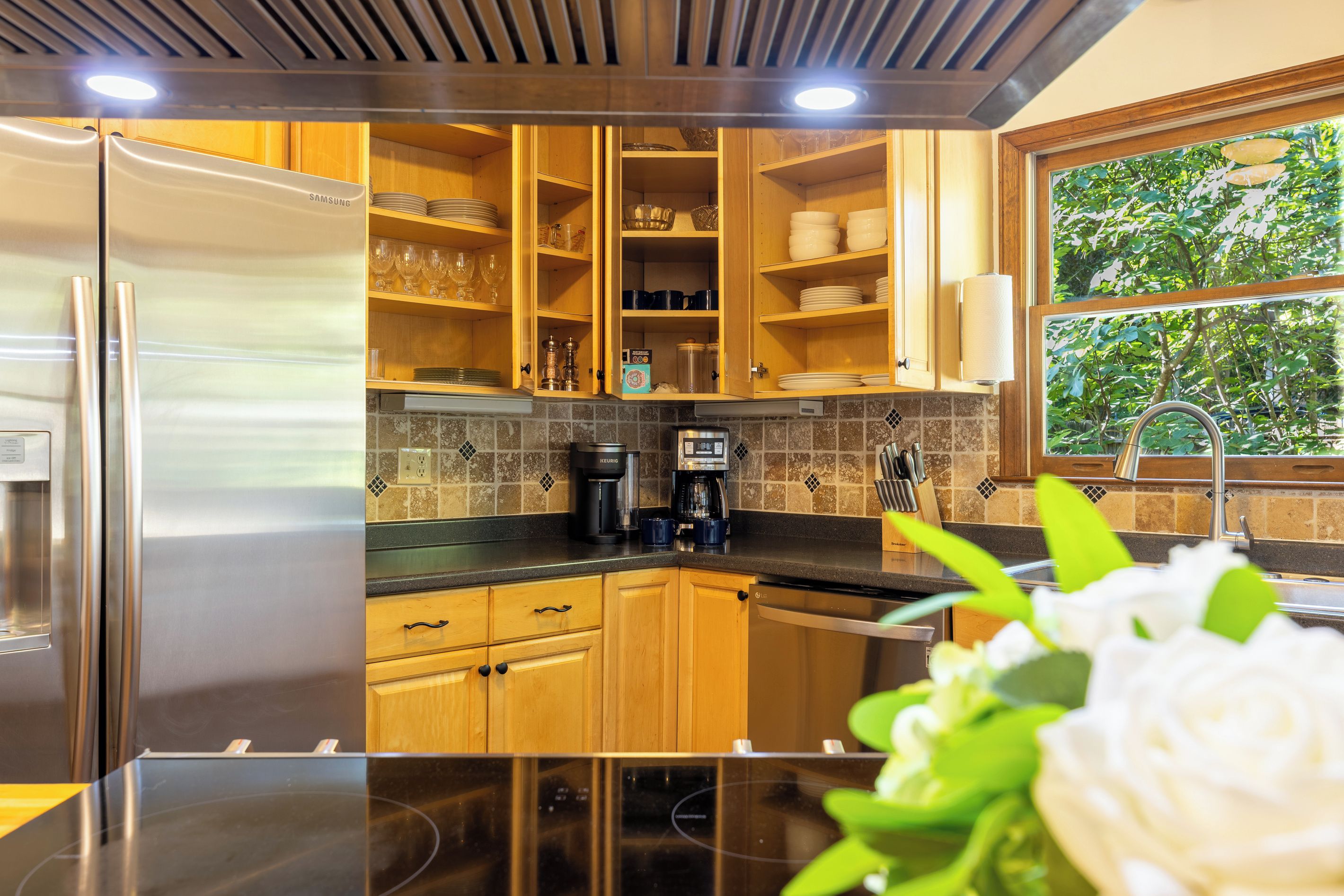 A modern kitchen with wooden cabinets, stainless steel appliances, and a coffee maker.
