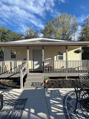 A single-story house with a front porch, a door, and two windows.