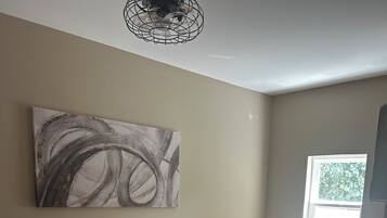 Un dormitorio con una cama, una ventana, una obra de arte en la pared y una lámpara en el techo.
