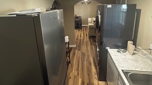 A kitchen with wooden flooring, stainless steel appliances, and a marble countertop.