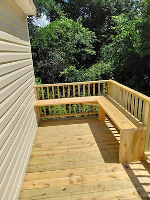 Une terrasse en bois dotée d’un banc intégré et d’une rambarde.