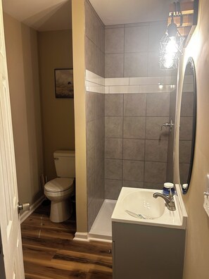 A bathroom with a toilet, shower, and sink.