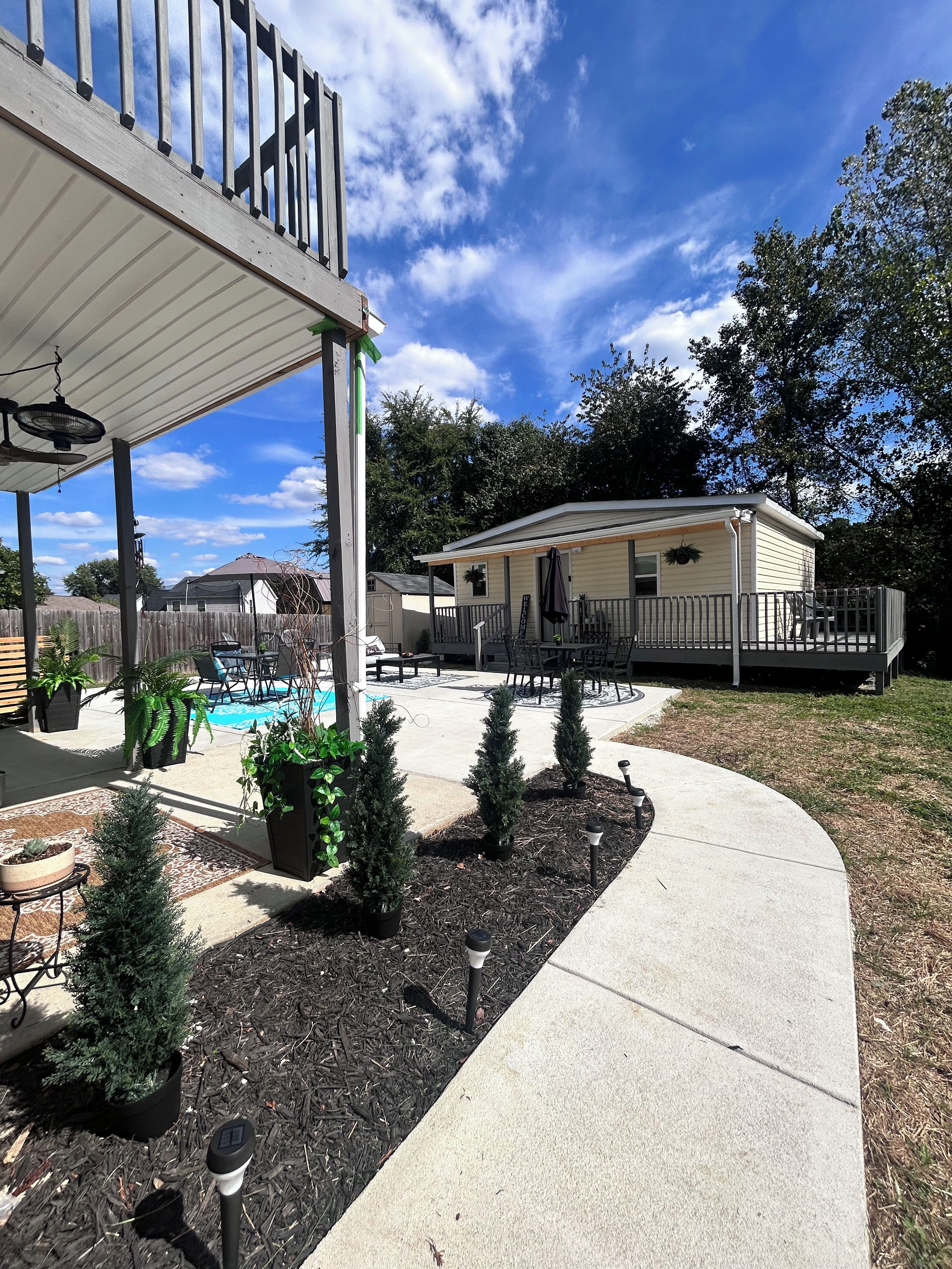 A residential area with a covered patio, a swimming pool, and a mobile home.