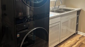 A kitchen with a built-in washer and dryer, a sink, and a window.