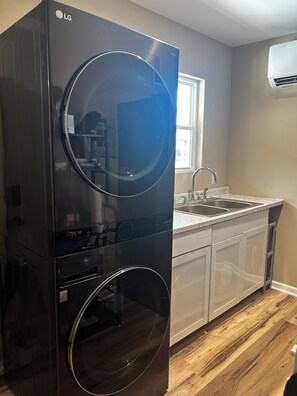 Une cuisine équipée d’un lave-linge et d’un sèche-linge intégrés, d’un évier et d’une fenêtre.
