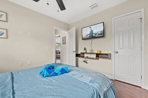 A bedroom with a bed, a television mounted on the wall, and a door. - Tremendous 2-bedroom house with AC in Panama City Beach (Panama City Beach)
