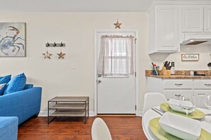 A modern kitchen with white cabinets, a dining table set with plates and glasses, and a small side table. - Tremendous 2-bedroom house with AC in Panama City Beach (Panama City Beach)