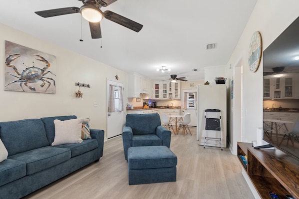 A modern living room with a blue sofa, a matching ottoman, and a ceiling fan. - Tremendous 2-bedroom house with AC in Panama City Beach (Panama City Beach)